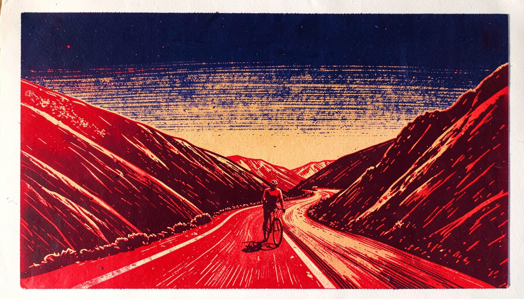 Linocut relief print of a lone cyclist on a winding mountain road at dawn, deep navy sky fading to warm ochre, bold carved lines and gritty texture